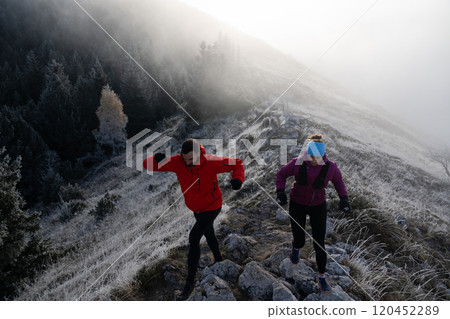 trail running couple man and woman running on a mountain path 120452289