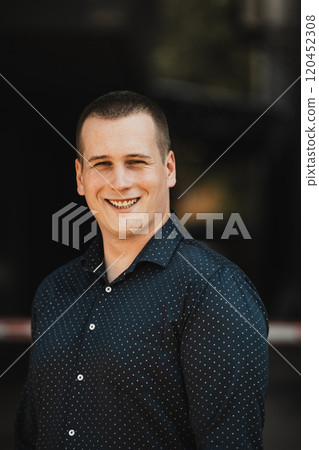 A portrait of a modern man, exuding confidence and style, against an outdoor backdrop, showcasing his charisma and fashionable demeanor. 120452308
