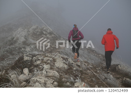trail running couple man and woman running on a mountain path 120452499