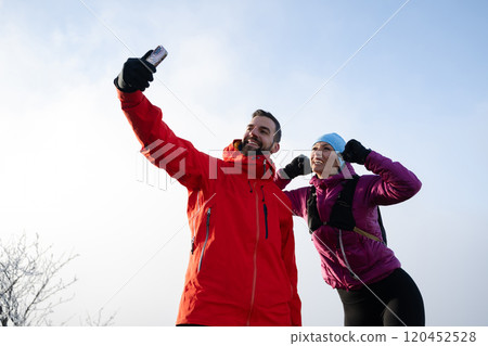 couple of hikers or track runners taking a selfie on the top of the mountain 120452528