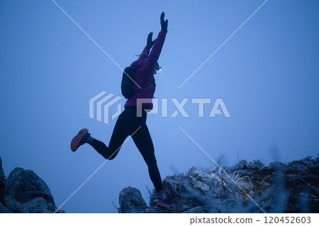 silhouette of a fitness woman trail runner jumping over a cliff and running to a rocky mountain top silhouette of a fitness woman trail runner jumping over a cliff and running to a rocky mountain top 120452603