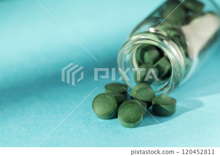 Spirulina pills in glass jars on blue background. Antioxidant nutrition. Bio-energy, biofuel, energy research. Copy space 120452811