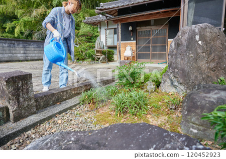 Woman taking care of the garden, watering, old house, countryside Woman taking care of the garden, watering, old house, countryside 120452923