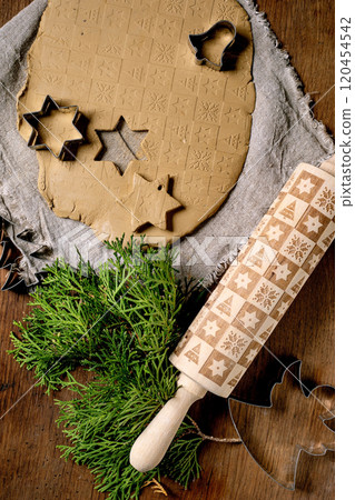 Decorating ceramics. A rolled slab of raw yellow clay with Christmas print on coarse fabric on wooden table. Textured rolling pin, cutout shapes, branches. Ceramic workshops, hand sculpting. Top view Decorating ceramics. A rolled slab of raw yellow clay with Christmas print on coarse fabric on wooden table. Textured rolling pin, cutout shapes, branches. Ceramic workshops, hand sculpting. Top view 120454542