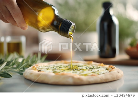 Drizzling olive oil on freshly prepared pizza topped with tomatoes and herbs in a cozy kitchen 120454679