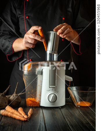 A chef skillfully extracts juice from fresh carrots using a sleek juicer, surrounded by vibrant vegetables. The warm, inviting kitchen atmosphere enhances the culinary artistry on display A chef skillfully extracts juice from fresh carrots using a sleek juicer, surrounded by vibrant vegetables. The warm, inviting kitchen atmosphere enhances the culinary artistry on display 120455968