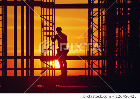 Silhouette of a construction worker working on top of a building at sunset. Silhouette of a construction worker working on top of a building at sunset. 120456425