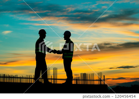 Silhouette of a construction worker working on top of a building at sunset. 120456454