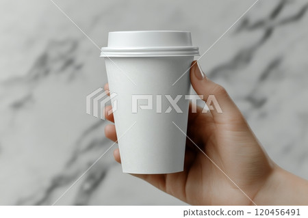 A person holding a plain white takeaway cup with a black lid against a gray wall A person holding a plain white takeaway cup with a black lid against a gray wall 120456491