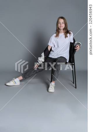 The young girl sits comfortably on a chair, her relaxed pose exuding quiet confidence. This image highlights the simplicity and authenticity of youthful moments in contemporary lifestyle. The young girl sits comfortably on a chair, her relaxed pose exuding quiet confidence. This image highlights the simplicity and authenticity of youthful moments in contemporary lifestyle. 120456943