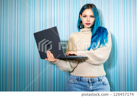 Portrait of beautiful blue haired hipster woman working standing with laptop, typing on keyboard and then turning around looking at camera satisfied and smiling. Problem solving,positivity and success 120457174