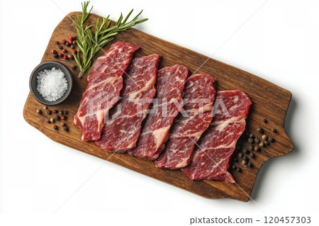 Fresh marbled beef steaks arranged on a wooden cutting board with herbs and salt Fresh marbled beef steaks arranged on a wooden cutting board with herbs and salt 120457303