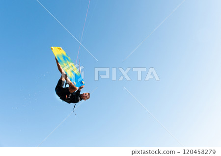 freestyle kiteboarding, freedom you can get. athlete hangs in the air during a trick on a kiteboard, on a clear blue sky freestyle kiteboarding, freedom you can get. athlete hangs in the air during a trick on a kiteboard, on a clear blue sky 120458279