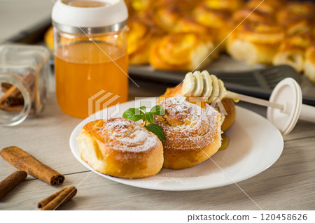 Pastries. Sweet buns with cottage cheese filling and honey in a plate on a wooden table Pastries. Sweet buns with cottage cheese filling and honey in a plate on a wooden table 120458626