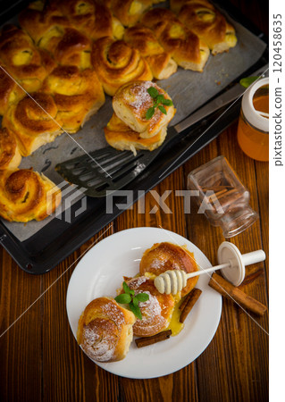 Pastries. Sweet buns with cottage cheese filling and honey in a plate on a wooden table Pastries. Sweet buns with cottage cheese filling and honey in a plate on a wooden table 120458635