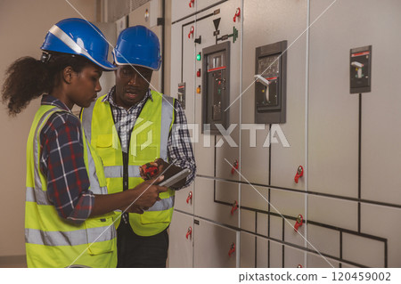 Electrical engineer team are working in control room. Electrical engineer man checking Power Distribution Cabinet in the control room Electrical engineer team are working in control room. Electrical engineer man checking Power Distribution Cabinet in the control room 120459002