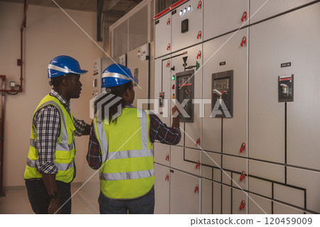 Electrical engineer team are working in control room. Electrical engineer man checking Power Distribution Cabinet in the control room Electrical engineer team are working in control room. Electrical engineer man checking Power Distribution Cabinet in the control room 120459009