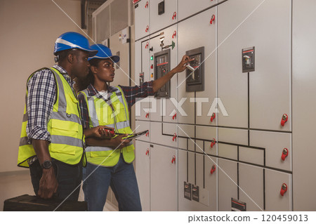 Electrical engineer team are working in control room. Electrical engineer man checking Power Distribution Cabinet in the control room Electrical engineer team are working in control room. Electrical engineer man checking Power Distribution Cabinet in the control room 120459013