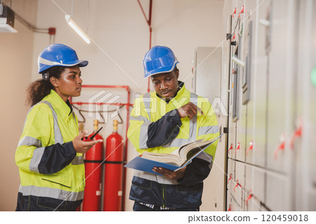 Electrical engineer team are working in control room. Electrical engineer man checking Power Distribution Cabinet in the control room 120459018