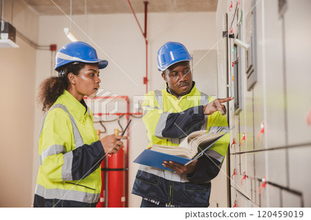 Electrical engineer team are working in control room. Electrical engineer man checking Power Distribution Cabinet in the control room Electrical engineer team are working in control room. Electrical engineer man checking Power Distribution Cabinet in the control room 120459019