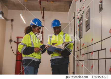 Electrical engineer team are working in control room. Electrical engineer man checking Power Distribution Cabinet in the control room Electrical engineer team are working in control room. Electrical engineer man checking Power Distribution Cabinet in the control room 120459022