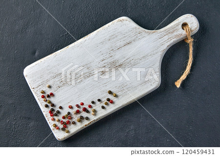 white wooden cutting board with scattered peppercorns on black stone table. top view with copy space white wooden cutting board with scattered peppercorns on black stone table. top view with copy space 120459431