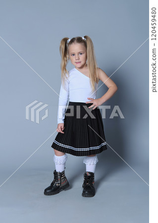 young girl models a trendy one-shoulder white top, black pleated skirt, and lace-trimmed socks paired with black boots. Her confident pose and stylish outfit make this image ideal for children s young girl models a trendy one-shoulder white top, black pleated skirt, and lace-trimmed socks paired with black boots. Her confident pose and stylish outfit make this image ideal for children s 120459480