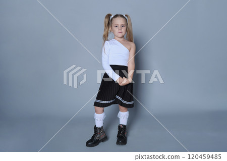 This stylish girl shows off a chic back-to-school look, with a black pleated skirt, white top, and black boots. Her outfit is a modern take on classic school uniforms, making this image perfect for 120459485