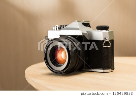 A vintage film camera sits elegantly on a table, showcasing timeless craftsmanship. 120459858