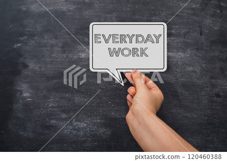 A hand holding a white sign that says everyday work 120460388