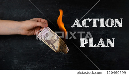 A hand holding a burnt dollar bill with the words Action Plan written below it A hand holding a burnt dollar bill with the words Action Plan written below it 120460399