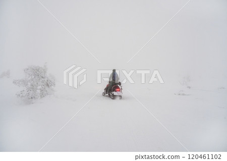 Snowmobile rider goes uphill in foggy frosty day . Snowmobile rider goes uphill in foggy frosty day . 120461102