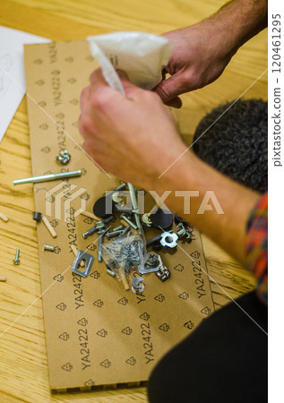 Furniture assembly man holding bolts, furniture assembling instructions and tool. High quality photo Furniture assembly man holding bolts, furniture assembling instructions and tool. High quality photo 120461295