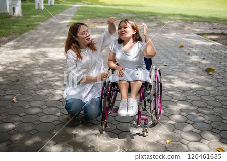 Young Woman in Wheelchair Enjoying a Walk in the Park with Her Best Friend on a Sunny Day Young Woman in Wheelchair Enjoying a Walk in the Park with Her Best Friend on a Sunny Day 120461685
