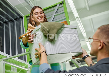 Dutch angle shot of man passing box with personal belongings to smiling girlfriend loading stuff into self storage unit in warehouse, while moving out or decluttering apartment together Dutch angle shot of man passing box with personal belongings to smiling girlfriend loading stuff into self storage unit in warehouse, while moving out or decluttering apartment together 120463384