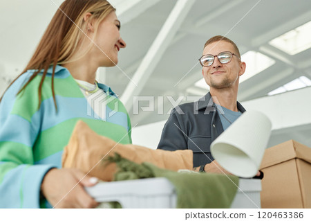 Medium shot of smiling man looking at cheerful girlfriend carrying boxes with personal belongings to self storage warehouse, while donating items to charity or moving out Medium shot of smiling man looking at cheerful girlfriend carrying boxes with personal belongings to self storage warehouse, while donating items to charity or moving out 120463386