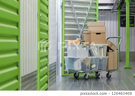 Background shot of cardboard boxes with personal belongings loaded on dolly cart in hallway of self storage warehouse during moving out or apartment decluttering, copy space Background shot of cardboard boxes with personal belongings loaded on dolly cart in hallway of self storage warehouse during moving out or apartment decluttering, copy space 120463409