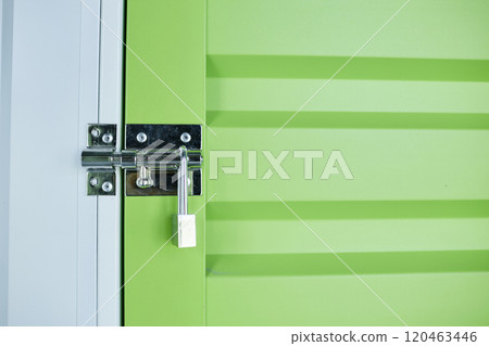 Background shot of green door leading to self storage unit with metal latch secured on lock at warehouse, copy space Background shot of green door leading to self storage unit with metal latch secured on lock at warehouse, copy space 120463446