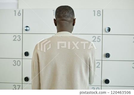 Hand of African American male office worker entering code on digital keypad of smart locker storing personal belongings in contemporary coworking, copy space 120463506