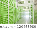 Background shot with diminishing perspective of aisle with green metal doors leading to self storage units closed on locks at warehouse, copy space 120463980