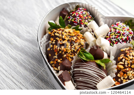 Handmade strawberry dessert coated in crushed nuts and white glaze in paper container. Fresh green leaves add a vibrant touch. Styled for festive look Handmade strawberry dessert coated in crushed nuts and white glaze in paper container. Fresh green leaves add a vibrant touch. Styled for festive look 120464114
