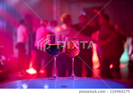 Red and white wine glasses at a lively party event 120464275
