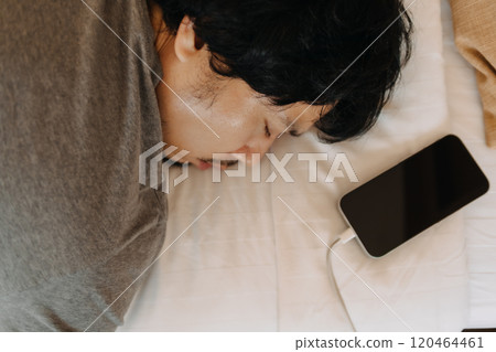 Close up face of sleepy man slept with his mobile phone left near his head. 120464461