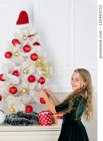 Child put christmas ornament ball on artificial white tree. Top christmas decorating ideas for kids room. Kids can brighten up christmas tree by creating their own ornaments. Girl celebrate christmas 120464552