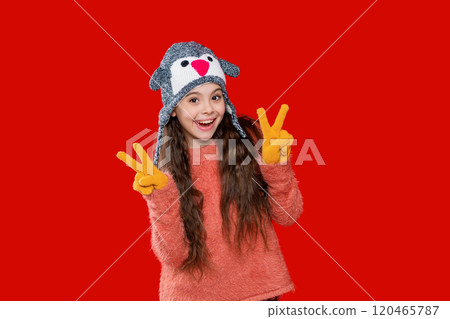 Trendy fashion outfit in winter. Winter girl child. Style portrait of teen girl in warm clothing and winter hat isolated on red. Knitted sweater and beanie hat. Peace Trendy fashion outfit in winter. Winter girl child. Style portrait of teen girl in warm clothing and winter hat isolated on red. Knitted sweater and beanie hat. Peace 120465787