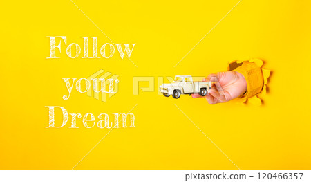 Hand holding a toy truck with the words follow your dream written below it Hand holding a toy truck with the words follow your dream written below it 120466357