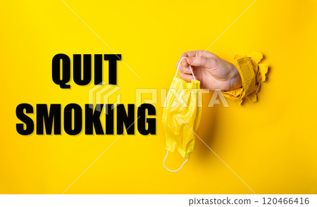 Person holding a yellow surgical mask with the words quit smoking 120466416