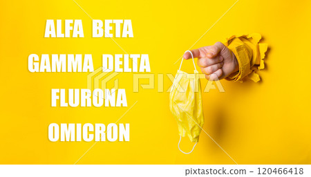 Yellow background with a hand holding a mask Yellow background with a hand holding a mask 120466418