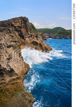 Cinematic aerial landscape shots of the beautiful island of Nusa Penida. Huge cliffs by the shoreline and hidden dream beaches with clear water and foaming wave. 120467399