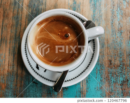 Cup of hot freshly brewed coffee, cappuccino, espresso in white cup on blue textured wooden table top view. Drinking beverage in cafe, coffee shop. Cup of hot freshly brewed coffee, cappuccino, espresso in white cup on blue textured wooden table top view. Drinking beverage in cafe, coffee shop. 120467796